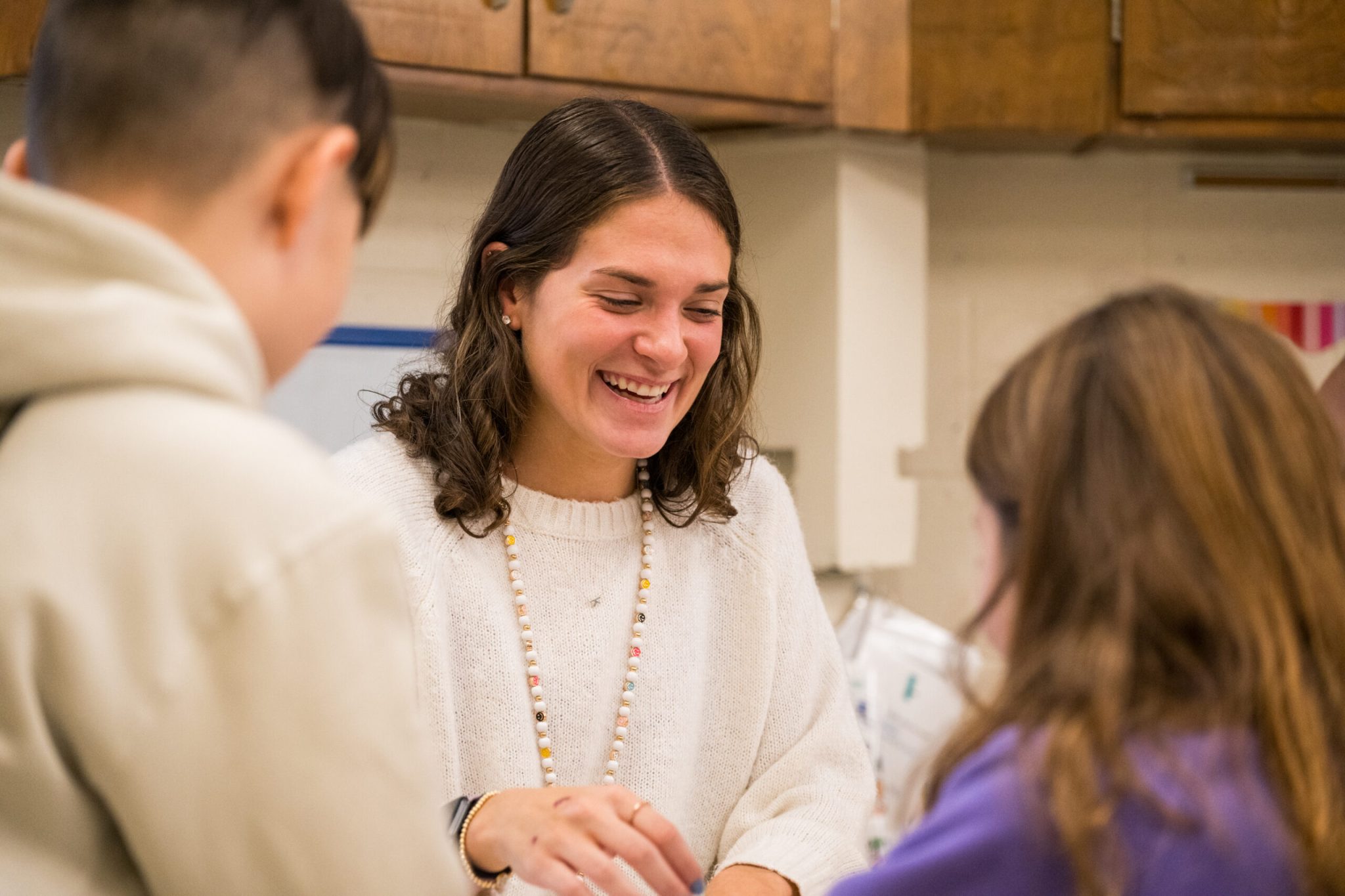 A woman facing college students wjile smiling